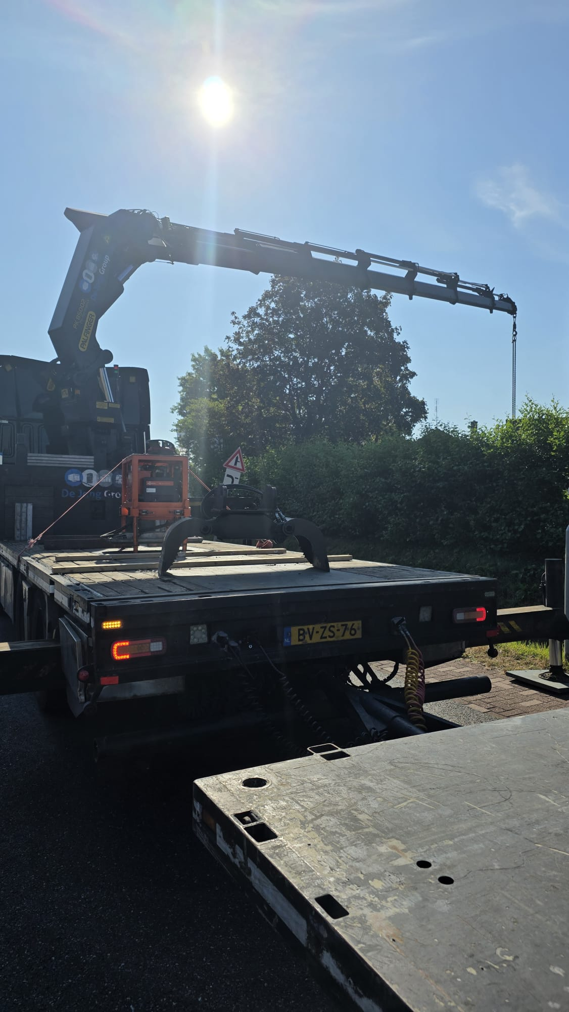 Laadkraan uitgeklapt op de dieplader tijdens laden