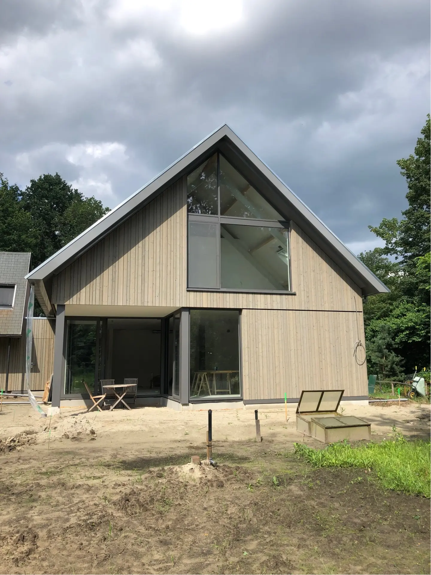 Houten schuurwoning met grote driehoekige aluminium puien in de topgevel