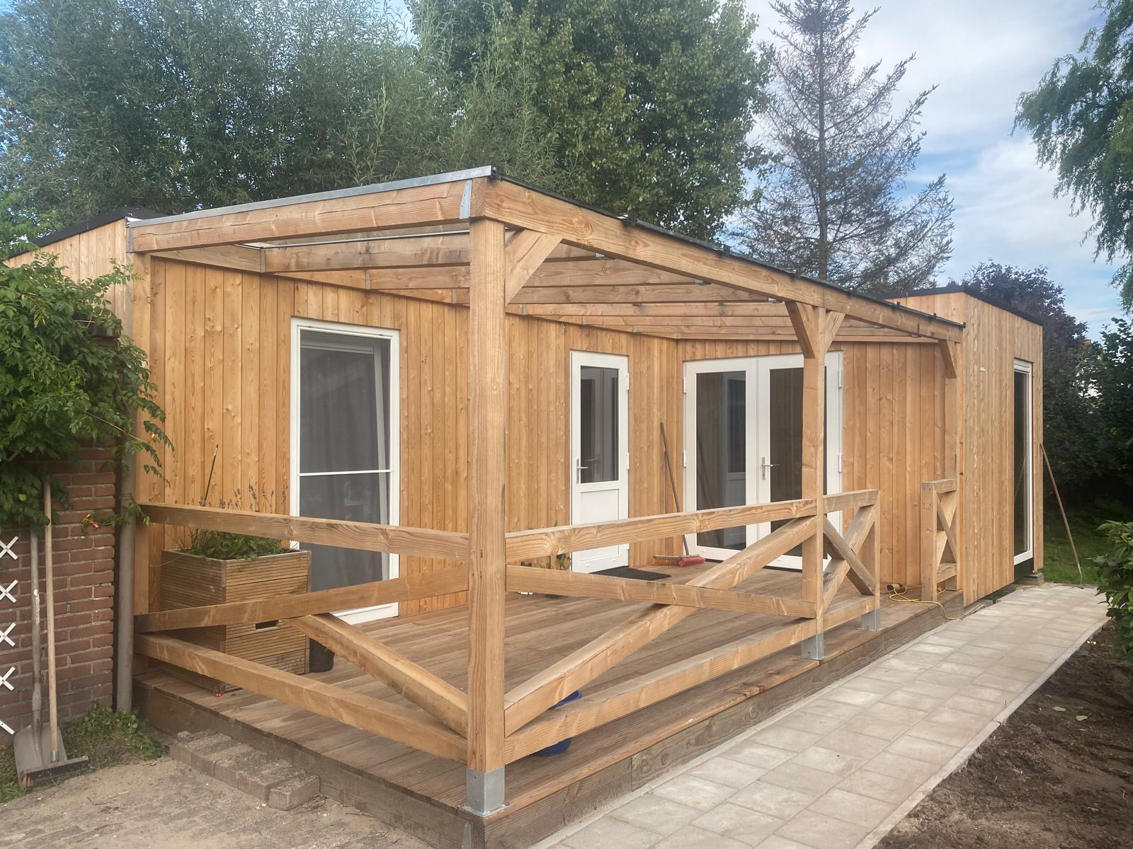 Houten unit met veranda, terras en balustrade in een tuin