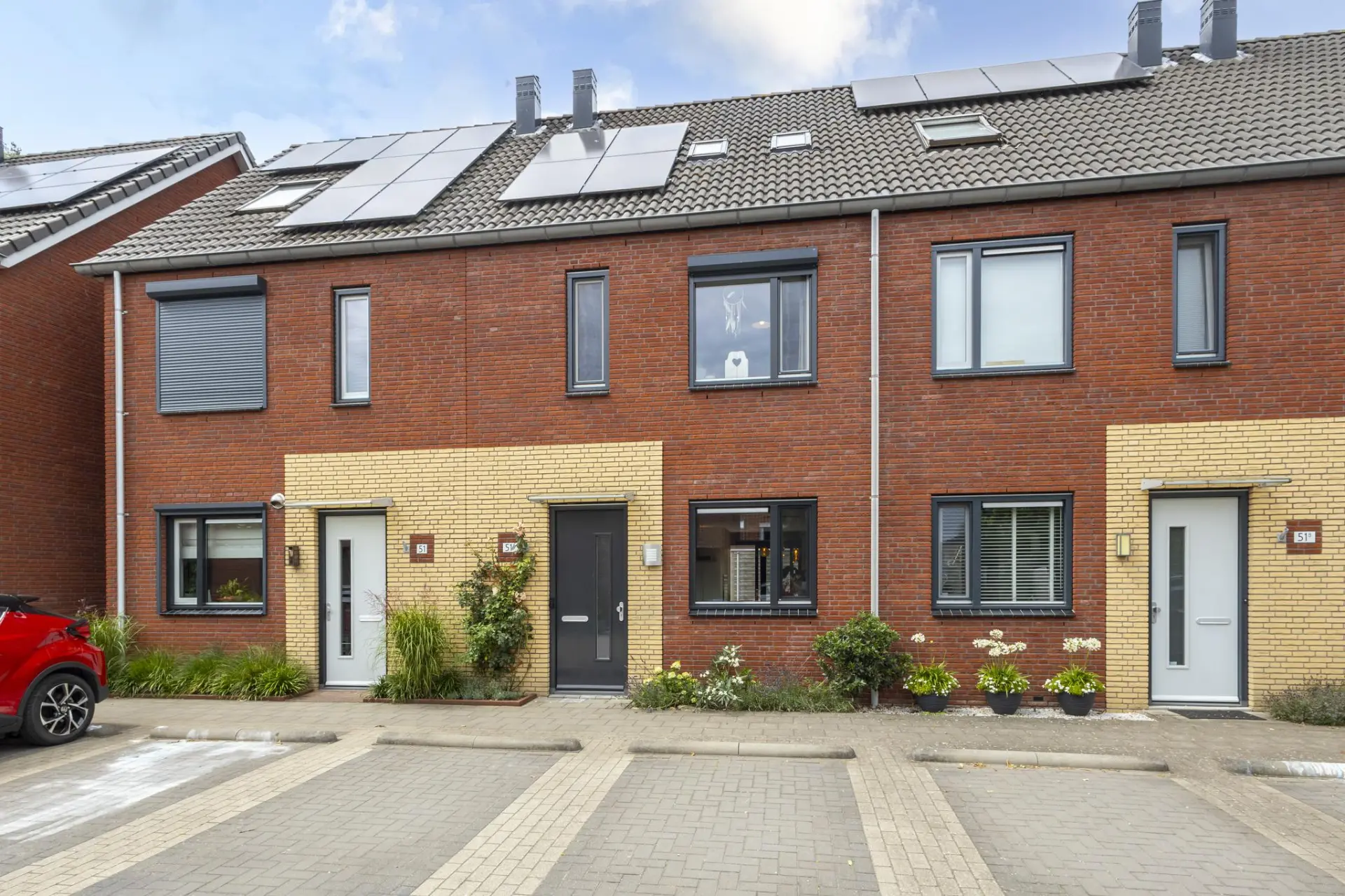 Rij moderne nieuwbouwwoningen met aluminium kozijnen en zonnepanelen