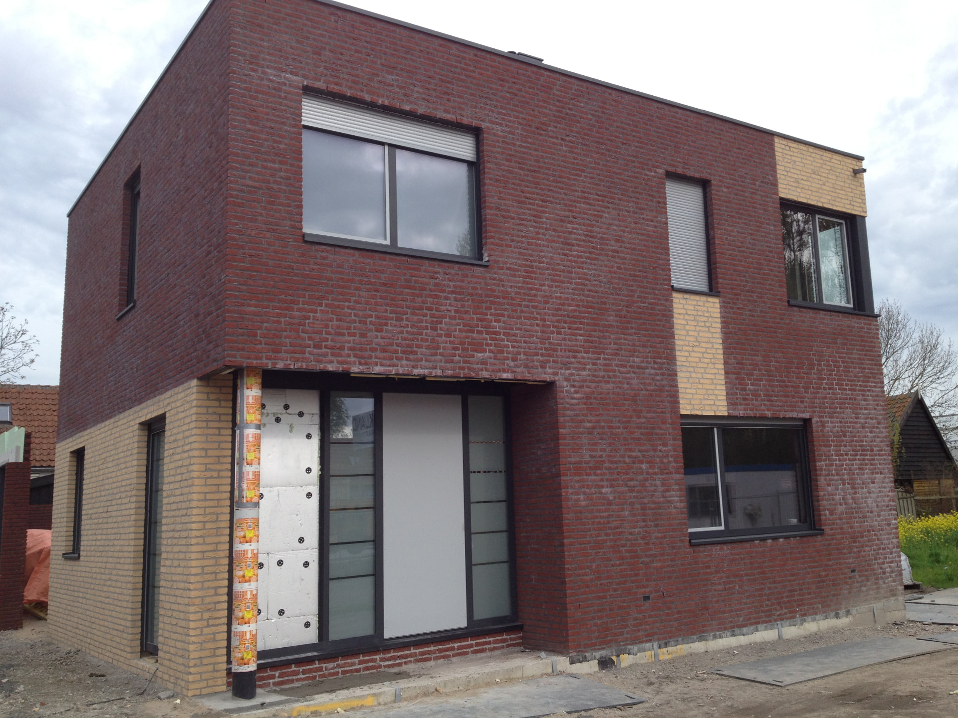 Nieuwbouwwoning in rode baksteen met gele accenten en aluminium kozijnen