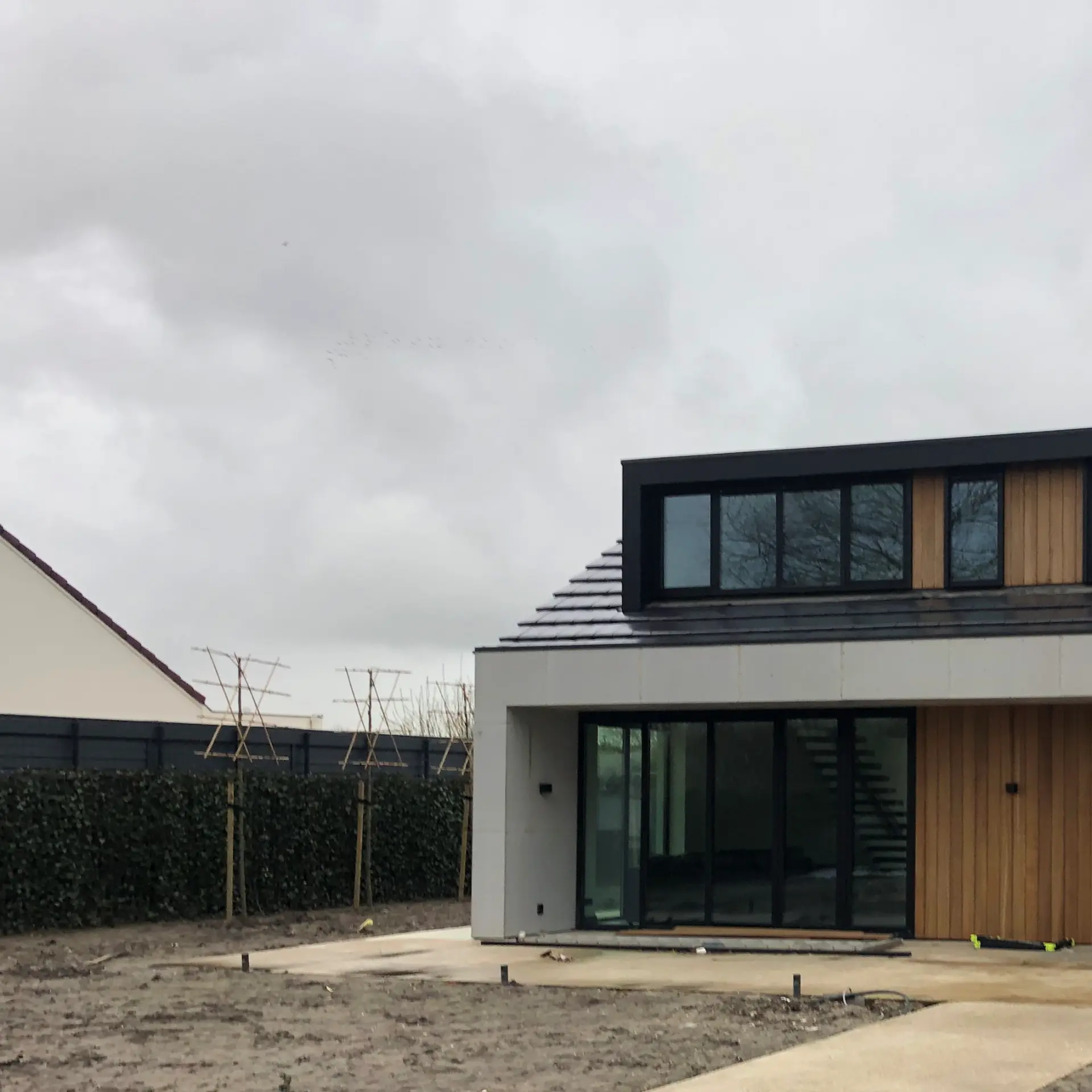 Nieuwbouwwoning met zwarte aluminium schuifpui en houten voordeur
