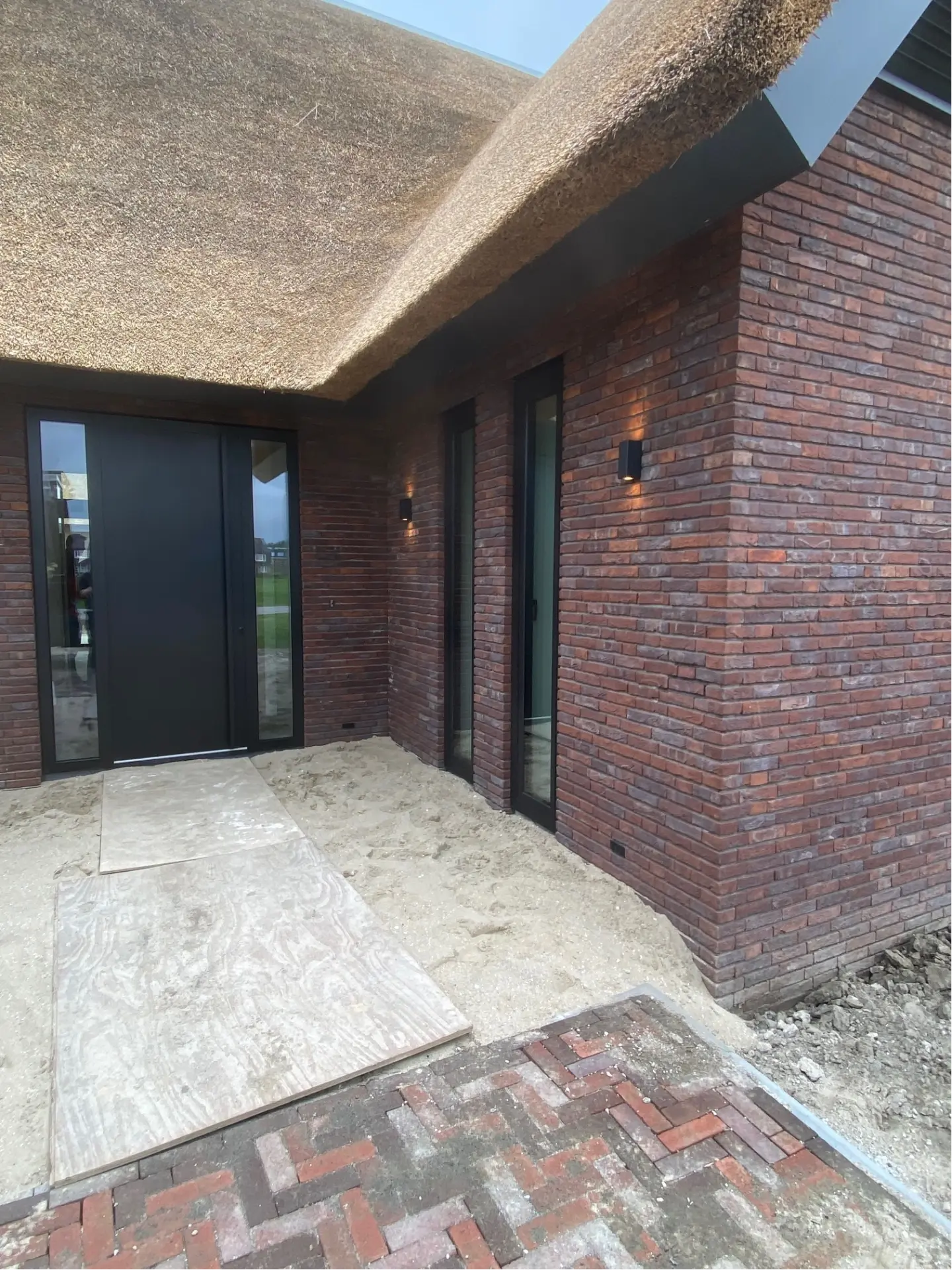 Rietgedekte woning met zwarte aluminium voordeur en smalle puien