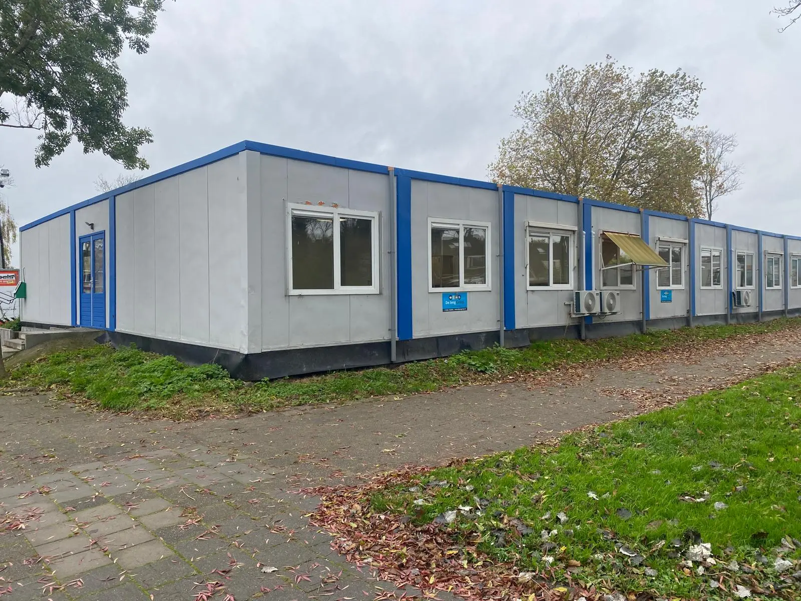 Langgerekt tijdelijk schoolgebouw van units met blauwe accenten