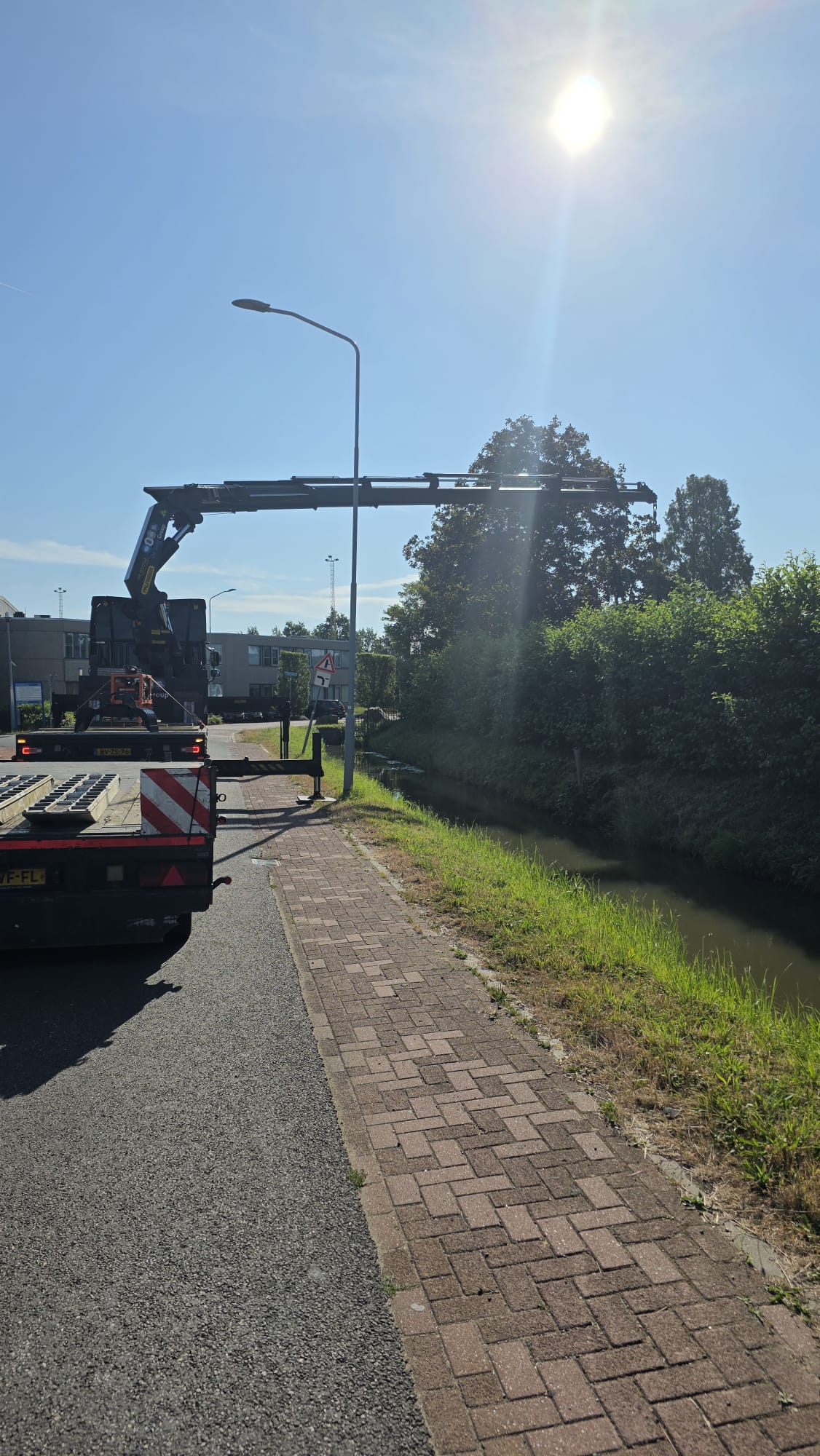 Uitgeschoven kraanarm boven de dieplader op locatie