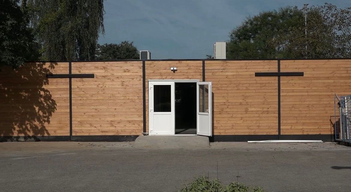 Unitgebouw met horizontale houten gevel en openstaande entreedeuren