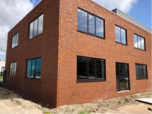Bedrijfsgebouw in rode baksteen met zwarte aluminium kozijnen