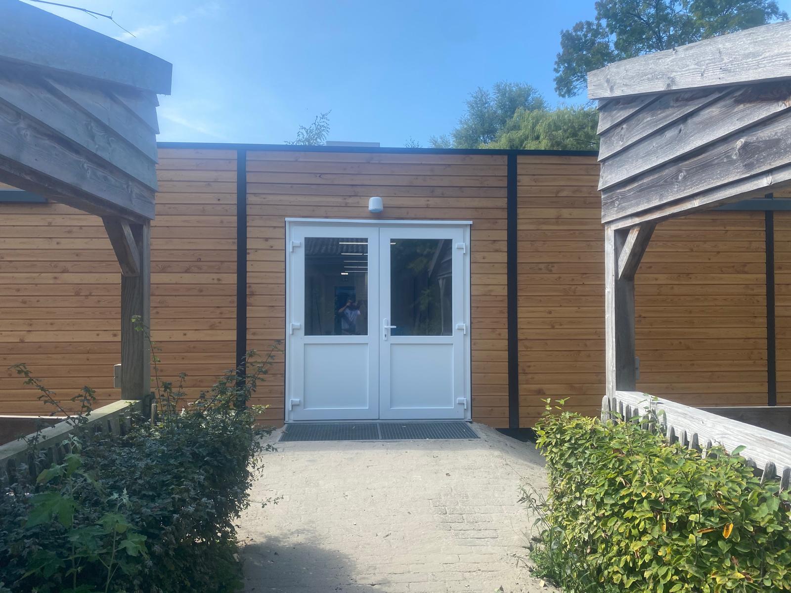 Entree met dubbele deuren in unitgebouw met houten gevel