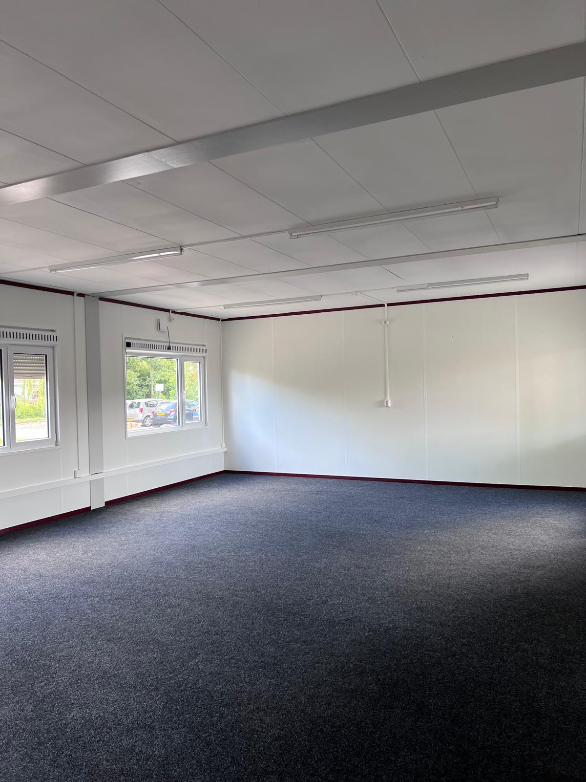 Ingerichte kantoorruimte in een unit met vloerbedekking en verlichting